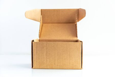 Open cardboard box on table on white backdrop. copy space. Packaging, online shopping and delivery...