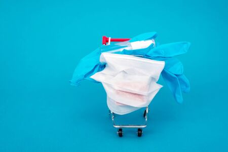 Medical surgical mask, sanitizer gel and blue lab gloves in shopping trolley for Supply of virus...