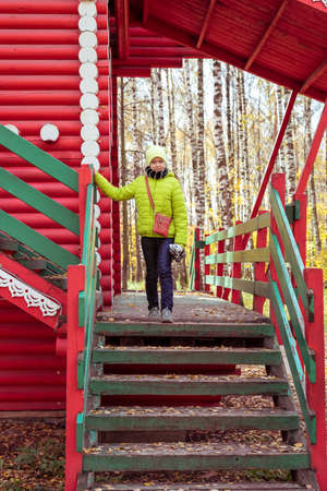 Beautiful teenager daughter in an green jacket plaing on the sport playground in the autumn park. Horizontal photoの写真素材
