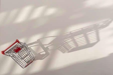 Grocery mini trolley cart casting a shadow on white table. Top view, flat lay.の写真素材