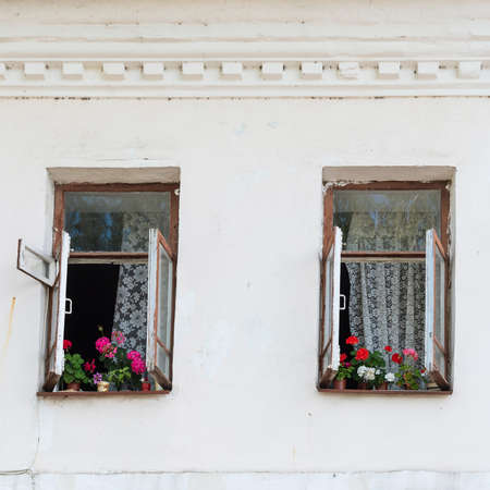Old rustic house with windows and blooming flowersの写真素材