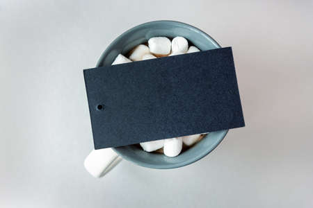 Blank black card on cup of cacao with marshmallow on greyの写真素材