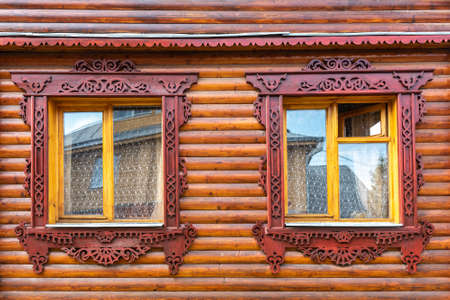 Rural house with decorated windows on wall made with logs