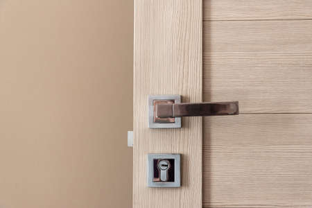 Close up stylish wooden door with knob and lock near beige wallの写真素材