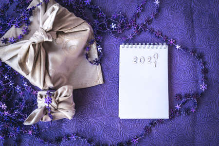 Christmas furoshiki wrapping. New Years gift wrapped in cloth and a notebook with numbers 2021の写真素材