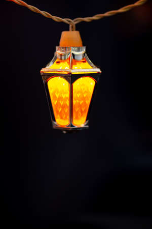 Glowing Xmas lights in black night. colorful Ffairy christmas lights with vintage lantern shaped lamps .の写真素材