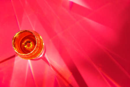 Wine Glass on red with sun light shadow surfaceの写真素材
