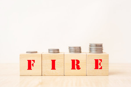 money coins on wooden blocks with text FIRE - financial independence retire earlyの写真素材