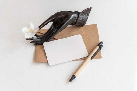 Holder with flower business card envelope and pen on tableの写真素材