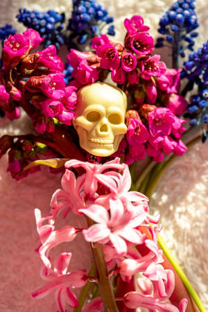 Flowers bouquet and toy skull on white fluffy fabricの写真素材