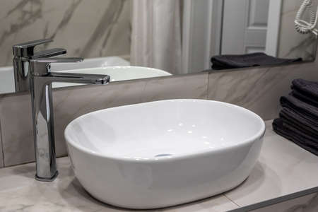 New vessel sink and shiny faucet near mirror in bathroomの写真素材