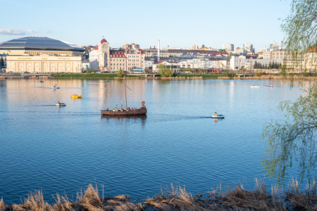 Traditional wooden rowing boat sails along tranquil riverのeditorial素材