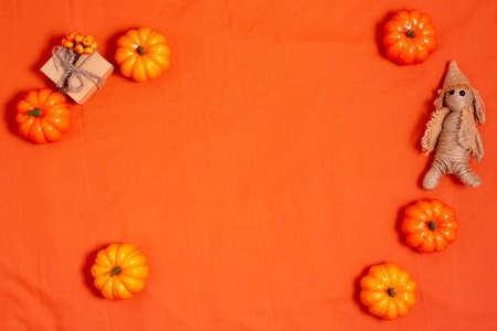 Orahge halloween background decorated pumpkin, gift box and straw doll, top view, flat layの写真素材