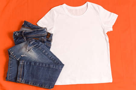 White t-shirt mockup and blue jeans on bright orange backgroundの写真素材