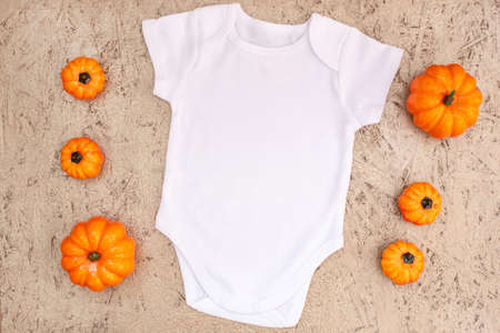 White baby bodysuit mockup with halloween decor on gold