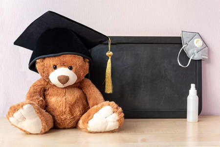 Teddy bear with cap sits near blackboard with medical itemsの写真素材