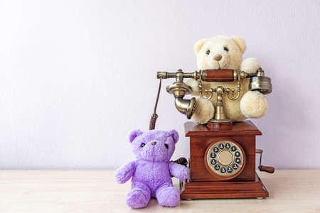 Small teddy bears around stylish vintage telephone on tableの写真素材