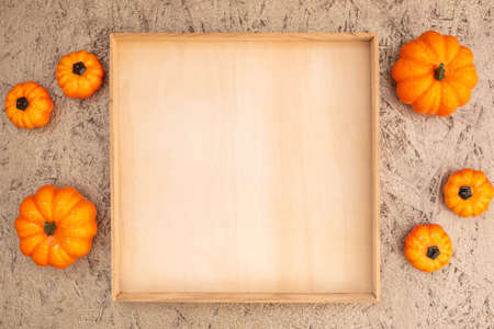 Decorative pumpkins and empty wooden crate on plywood