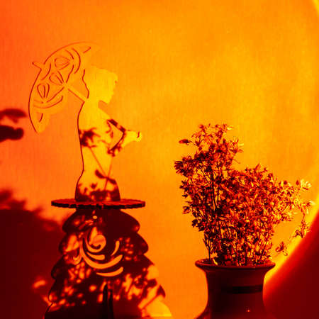 Statue of woman with umbrella at twigs illuminated by light