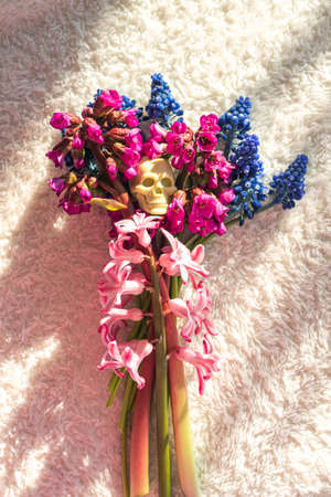Bouquet of spring flowers and toy skull on terry fabricの写真素材