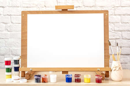 Blank white paper for painting on wooden easel on table at home studioの写真素材