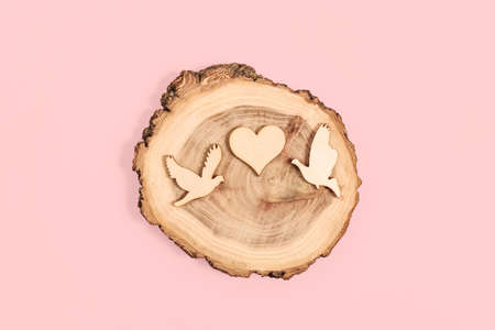 Wooden figurines of doves and heart on pink background.b Valentines day card