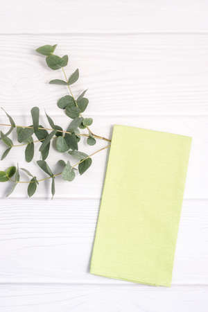 Green dish towel and twig of Eucalyptus on white wood tableの写真素材