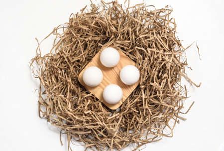 Natural chicken eggs on a wooden stand on white background