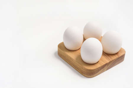 Natural chicken eggs on a wooden stand on white backgroundの写真素材
