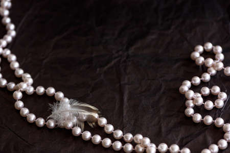 Pink pearls on black paper background with copy space.
