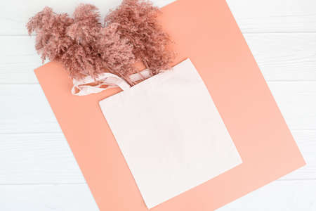 Fall mockup with tote bag blank and dry reeds on white wood background. Boho shopping bag mock up grass for decoration design. Sale mockup. Handbag ecology concept.の写真素材