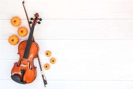 Violin, bow and pumkin on white wood background. Flat lay, top view, copy space. Concept of classical music and autumn, bowed string musical instrumentの写真素材