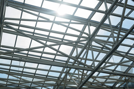Sunlight breaks through abstract metal frame and glass wall