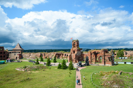Historical fortress ruins on green meadow against blue skyの写真素材