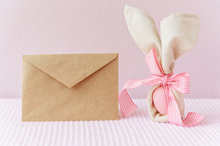 Easter mockup with craft envelope and bunny ears easter eggs on pink cover background.の写真素材