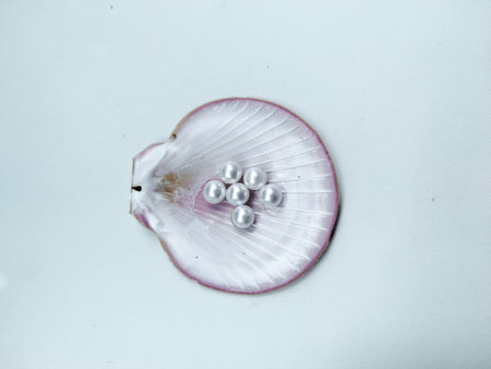 Close-up of white pearls placed on purple seashell with light background.
