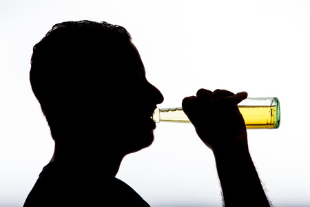 alcoholic with bottle in shadowの写真素材