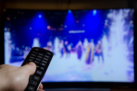 Watching TV and using a remote controller.の写真素材