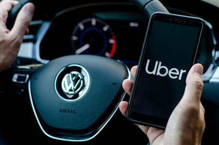 Soest, Germany - August 4, 2019: Uber driver holding smartphone in Volkswagen car. Uber is an...