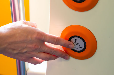 Hand presses a button for disabled people on the trainの写真素材