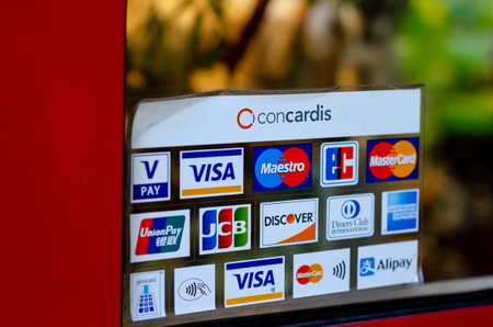 Munster, Germany - April 18, 2022: Various payment options, Discover, JCB, UnionPay, Mastercard, Diners Club International, VISA and Alipay, are seen on the door sticker in a store.のeditorial素材
