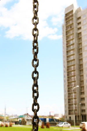 strong iron chain on blue sky and buildingの写真素材