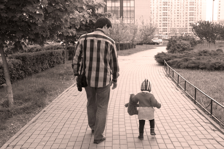 Father and a little one-year-old daughter are walking along the avenue. Model back, face is not visible. Stylized and smeared under old photos.の写真素材