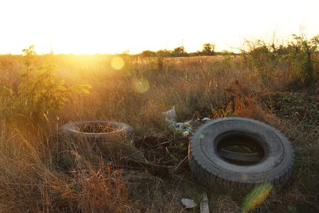 spontaneous dump discarded tires and household rubbish . garbage dump on the side of a dirt road. The problem of recycling garbage, tires and environmental pollution by humans.の写真素材