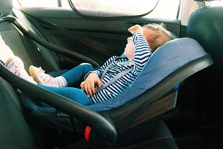 baby smile in a safety car seat. security. one year old child girl in blue wear sit on auto cradle. Rules for the Safe Transport of Children. Holders.の写真素材