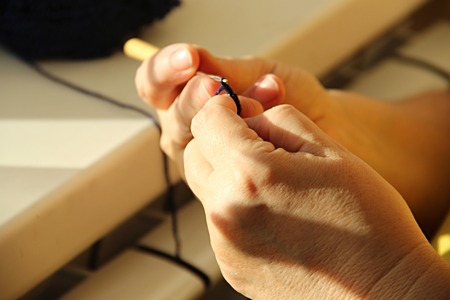 Old woman's hands knitting. the old woman knits crocheted from dark blue yarn. Grandmother knitting...