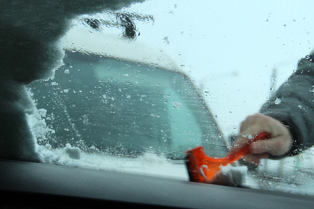 Transportation, winter, weather, people and vehicle concept - man cleaning snow from car with...