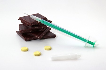 Insulin syringe, dark bitter chocolate and yellow tablets on white background close up. Concept diabetic chocolate or diet with diabetesの写真素材