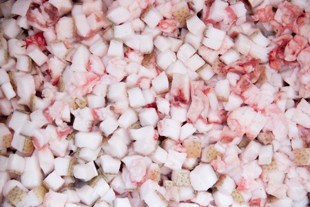 background diced pork fat for cooking smaltse. Cubed pork fat being rendered to make scratchings.の写真素材