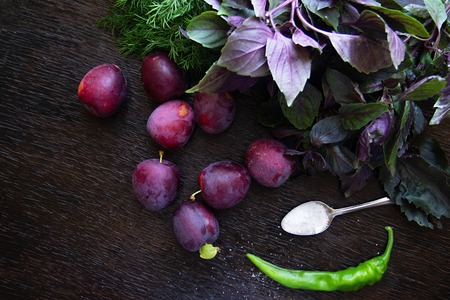 georgian plum sauce tkemali recipes products. Ripe cherry plum, basil, dill, salt and spicy green chili peppers on a black wooden background.の写真素材